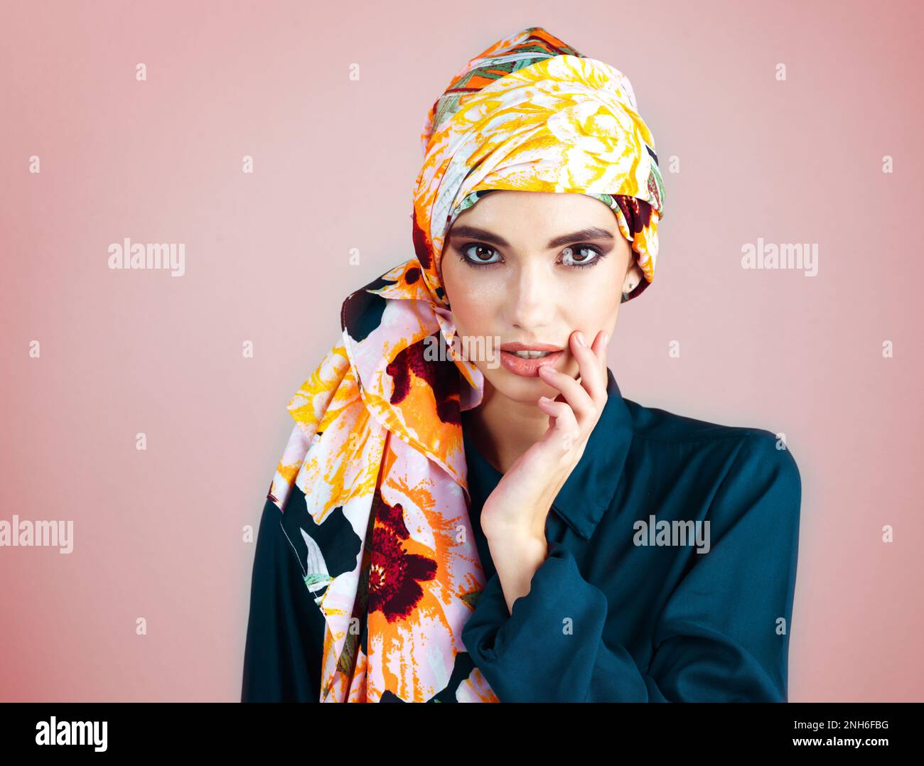 If looks could kill. Studio portrait of a confident young woman wearing a colorful head scarf while posing against a pink background. Stock Photo