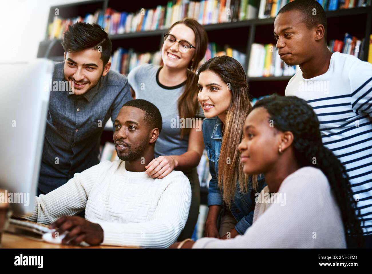 Study hard, study smart. a group of young students using a computer together in a college library. Stock Photo