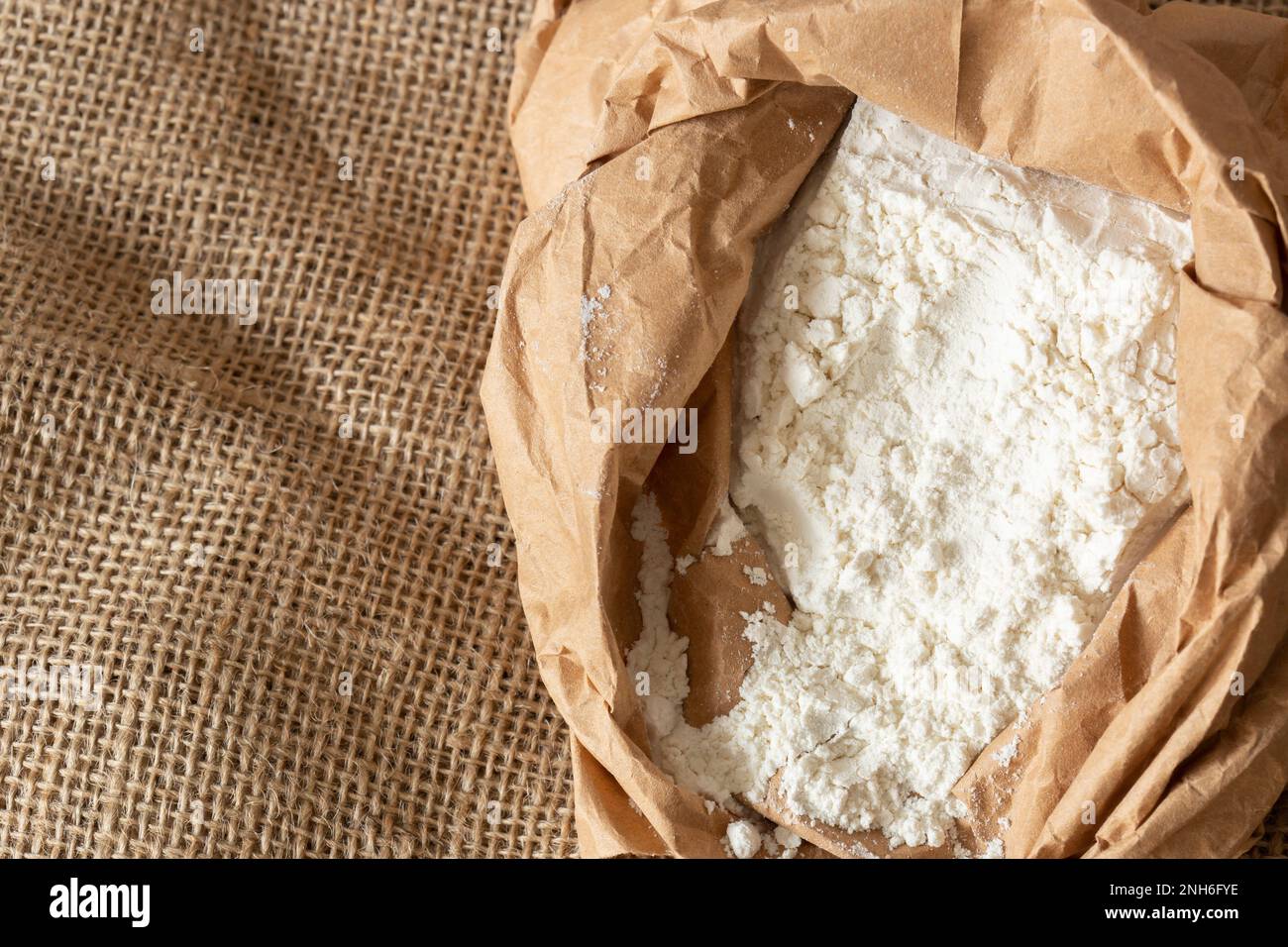 Plain white flour in a brown paper bag on hessian sack cloth. Eco