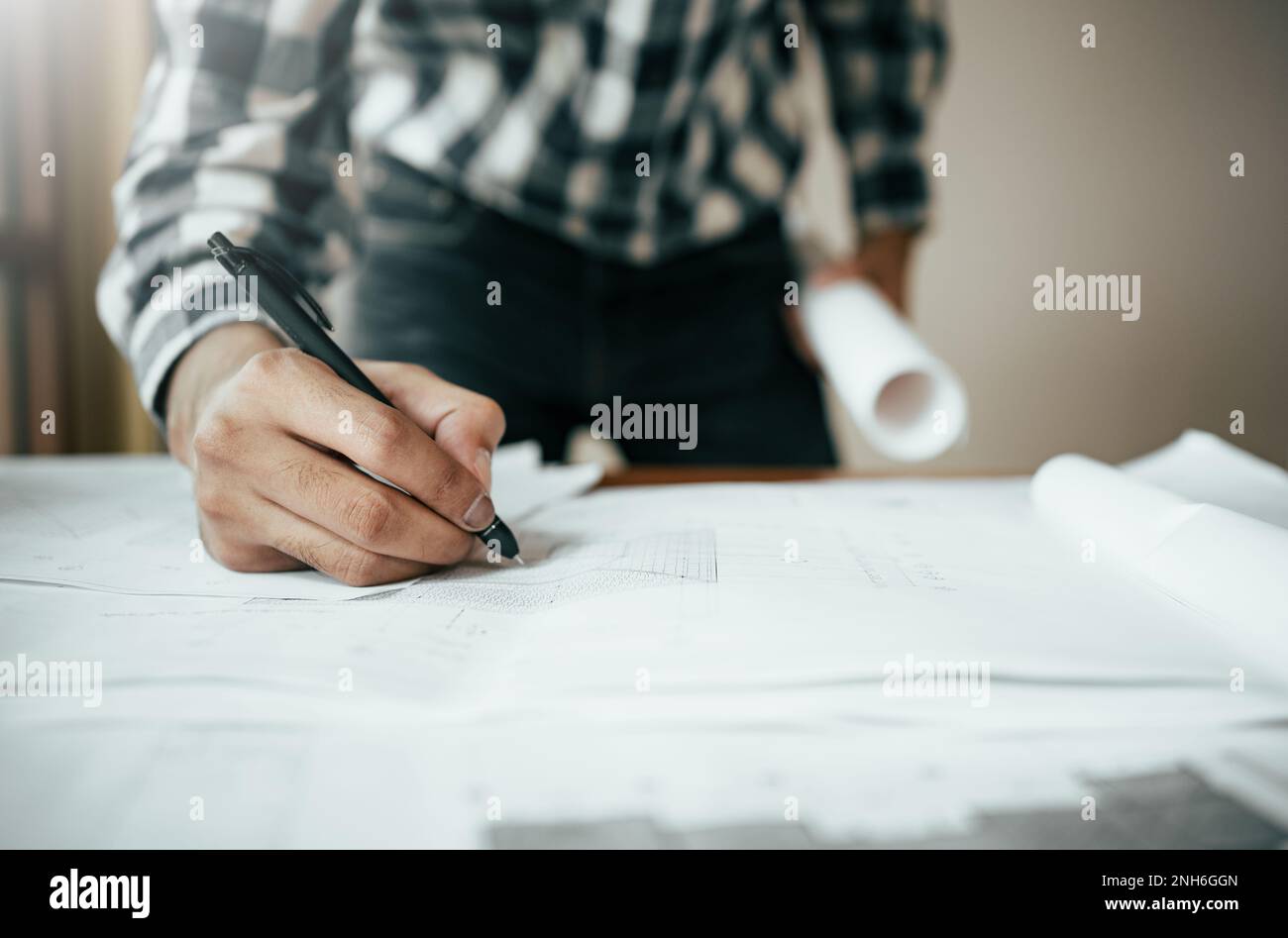 Close-up of asian male civil engineer working on blueprint architecture project on construction site at work desk in office. Stock Photo