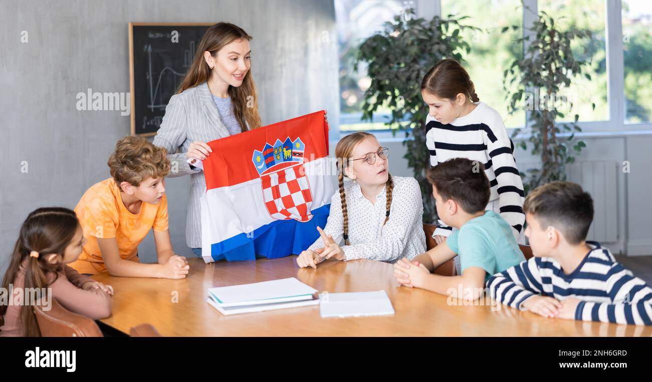 Smiling young woman teacher showing national flag of Croatia and ...