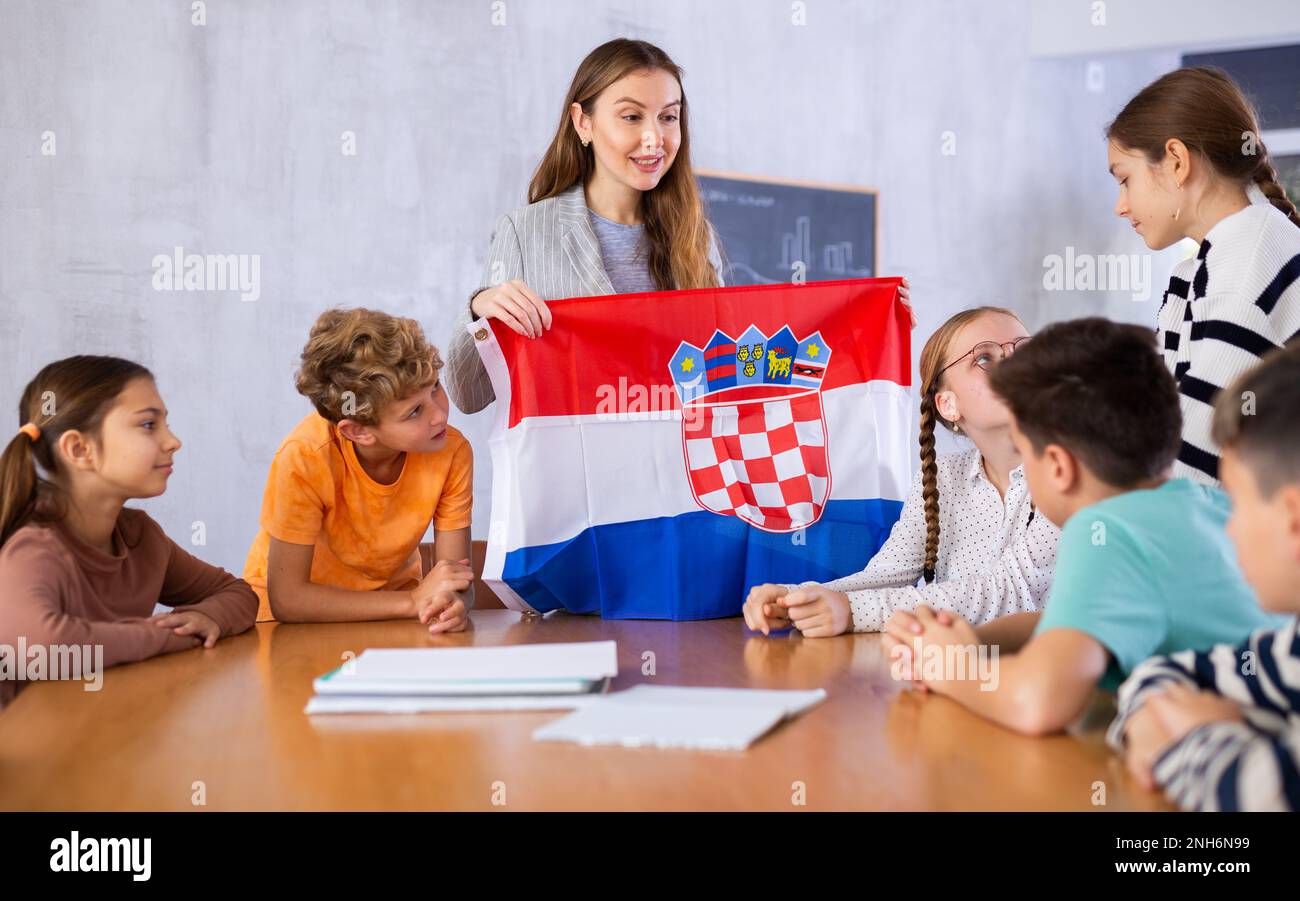 Smiling young woman teacher showing national flag of Croatia and ...