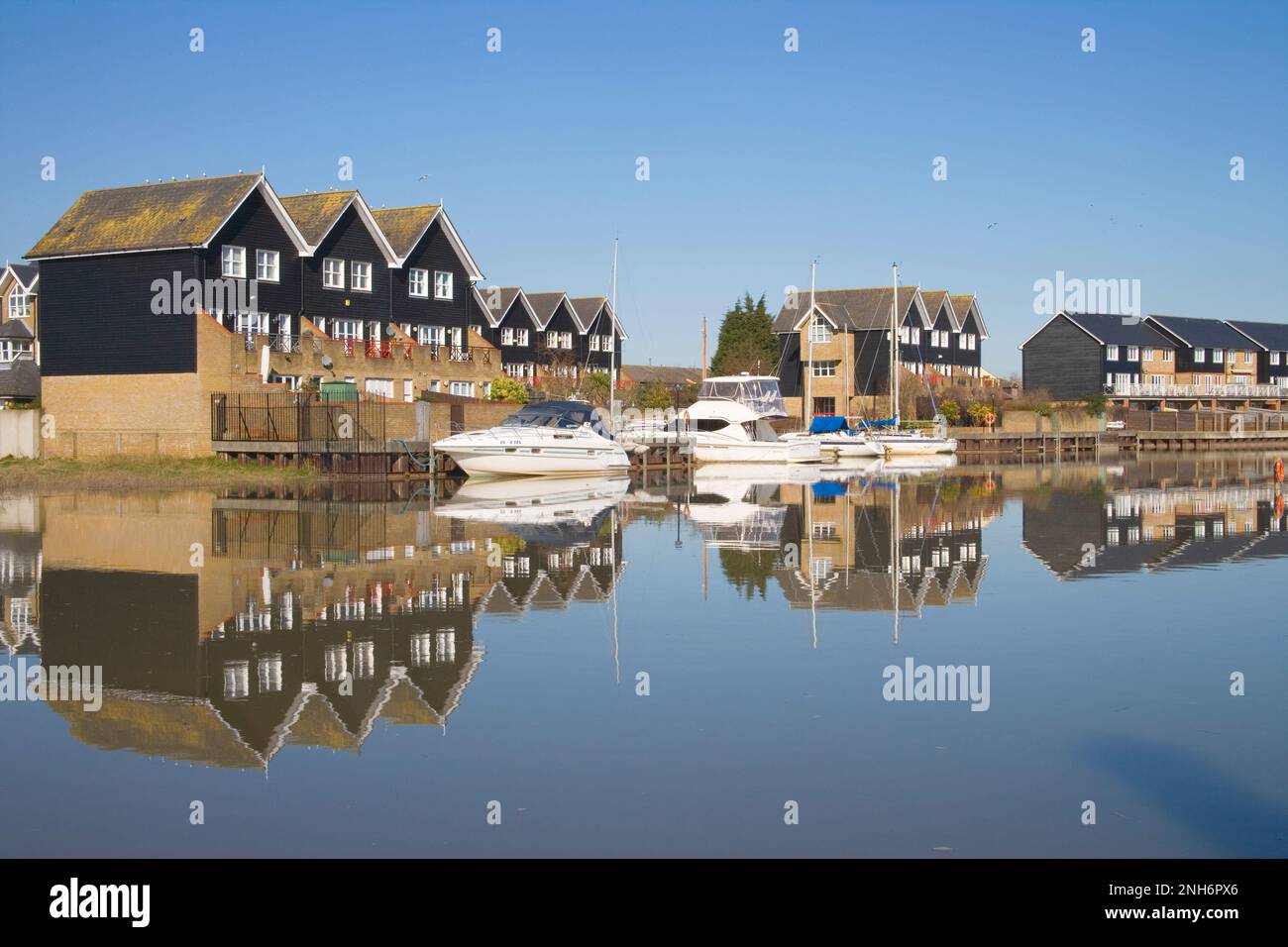 modern houses and boats moored along the river Swale in Faversham in north Kent Stock Photo