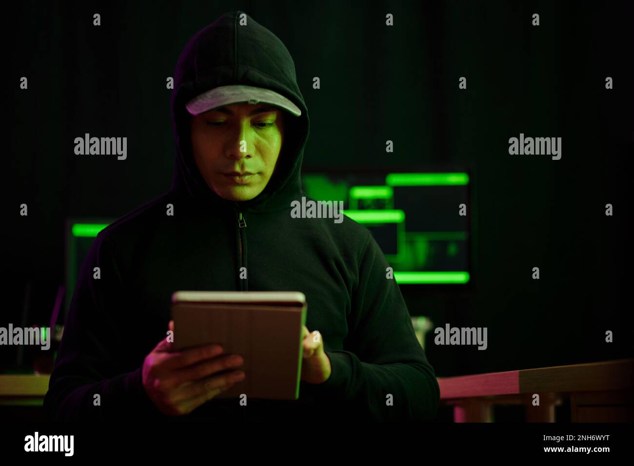 Portrait of hacker using application on tablet computer when launching cyberattack Stock Photo