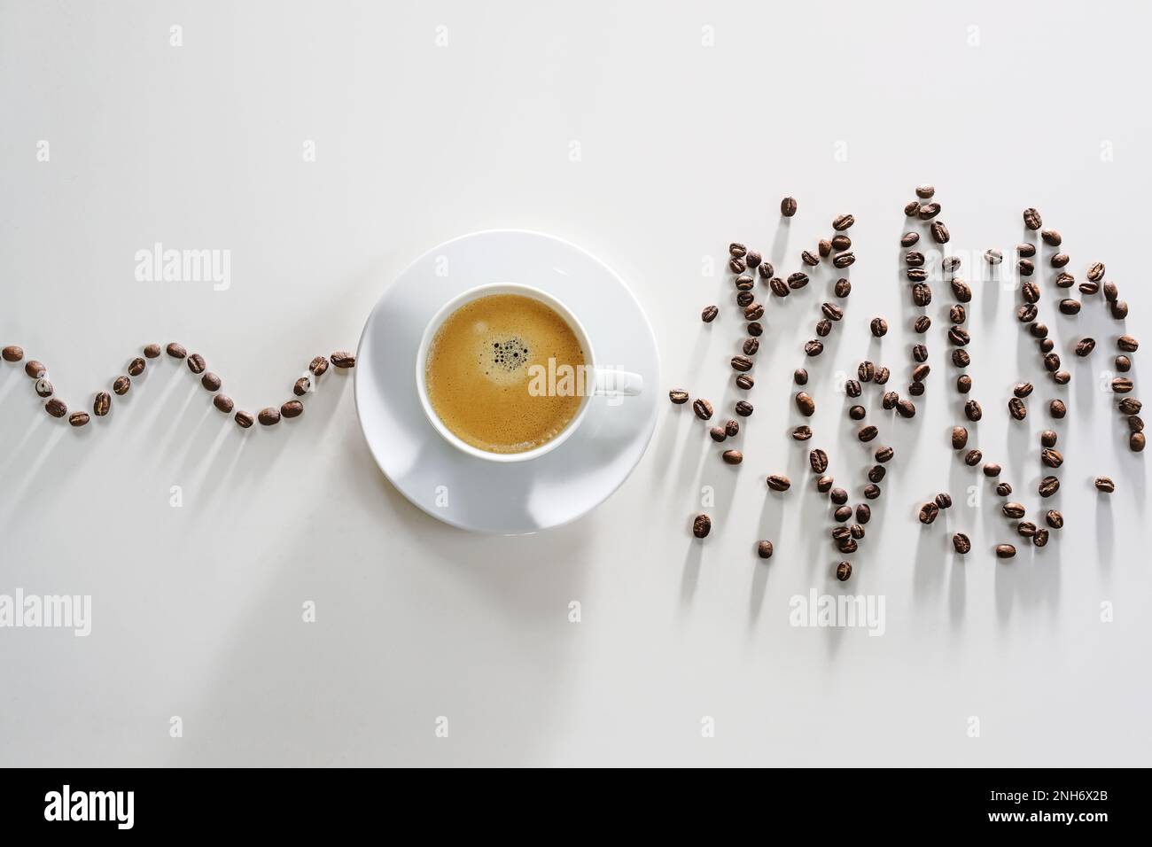 Coffee beans in a calm curve lead to a coffee cup, afterwards the beans show an exited messy pattern, concept for over stimulating effect on heart rhy Stock Photo