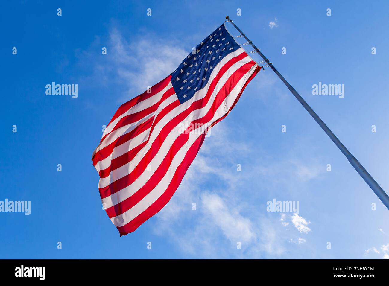 Closeup of large American flag waving in front of blue sky. US flag - American Flag waving in wind. Stock Photo