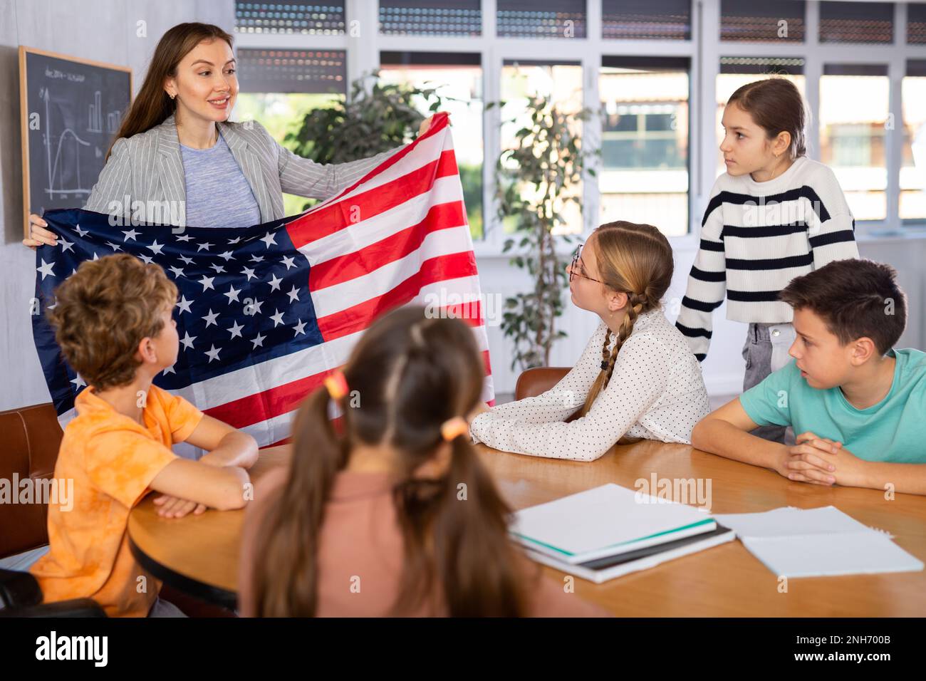 Teacher talks about the country and the national flag of United States of America in a geography lesson. Teenage students listen carefully Stock Photo