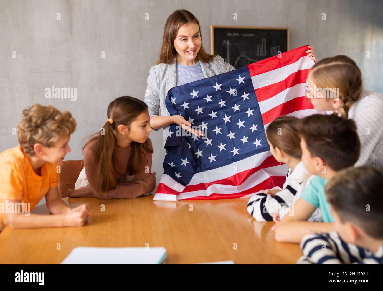 Geography lesson in school class - teacher talks about United States of America, holding flag in his hands Stock Photo
