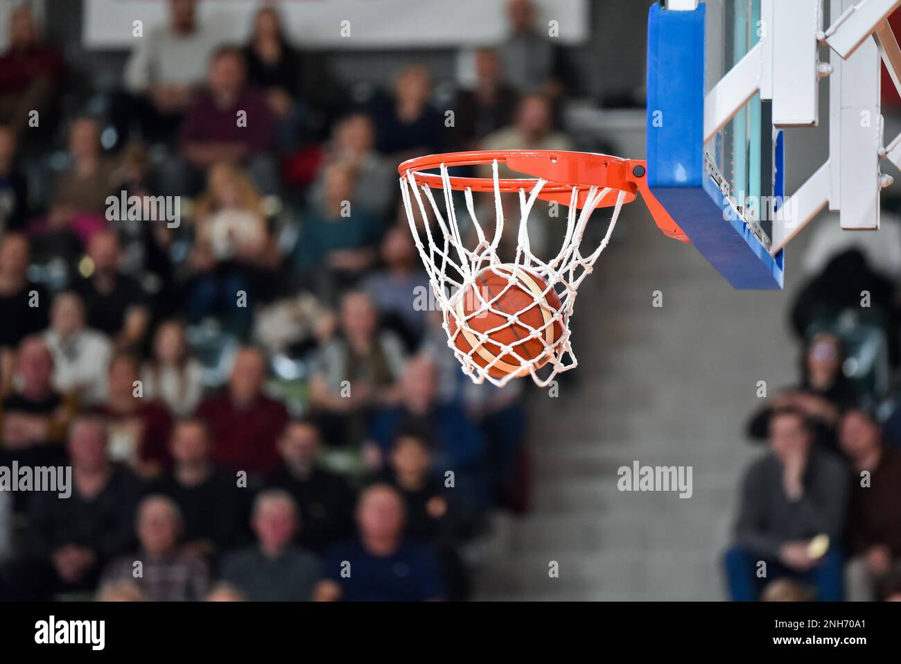 The ball falling into the basket during a basketball game Stock Photo