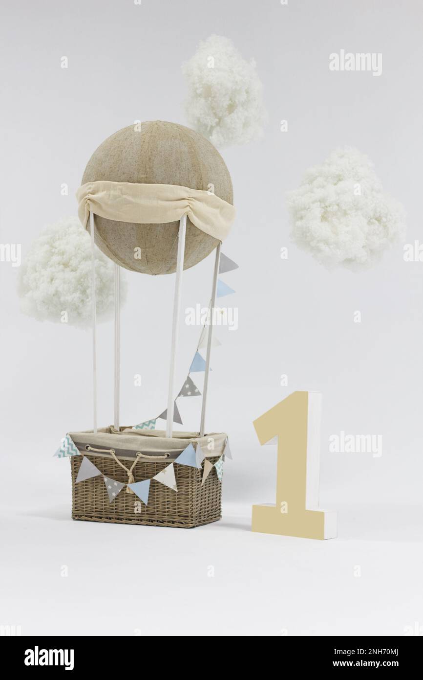 A decorative holiday balloon with a basket, tags and clouds installed in a photo studio and a big number one. Beautiful decor for festive photo shoots Stock Photo