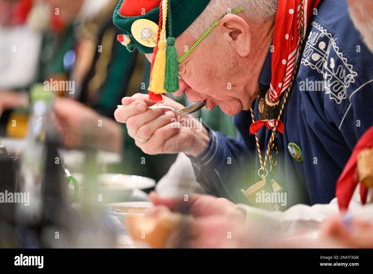 Riedlingen, Germany. 21st Feb, 2023. Kretschmann, Prime Minister of Baden-Württemberg (center, The Greens/ Bündnis 90, M), eats a plate of frog tripe at City Hall on Shrove Tuesday. More than 300 fools from the Gole 1865 jesters' guild take part in cigar smoking, the 192nd Froschkuttel meal and the subsequent slide out of the town hall, and later plan to gamble through the city. Frog tripe is a specialty of Riedlingen. It is sliced beef stomach pickled in vinegar. Credit: Felix Kästle/dpa/Alamy Live News Stock Photo