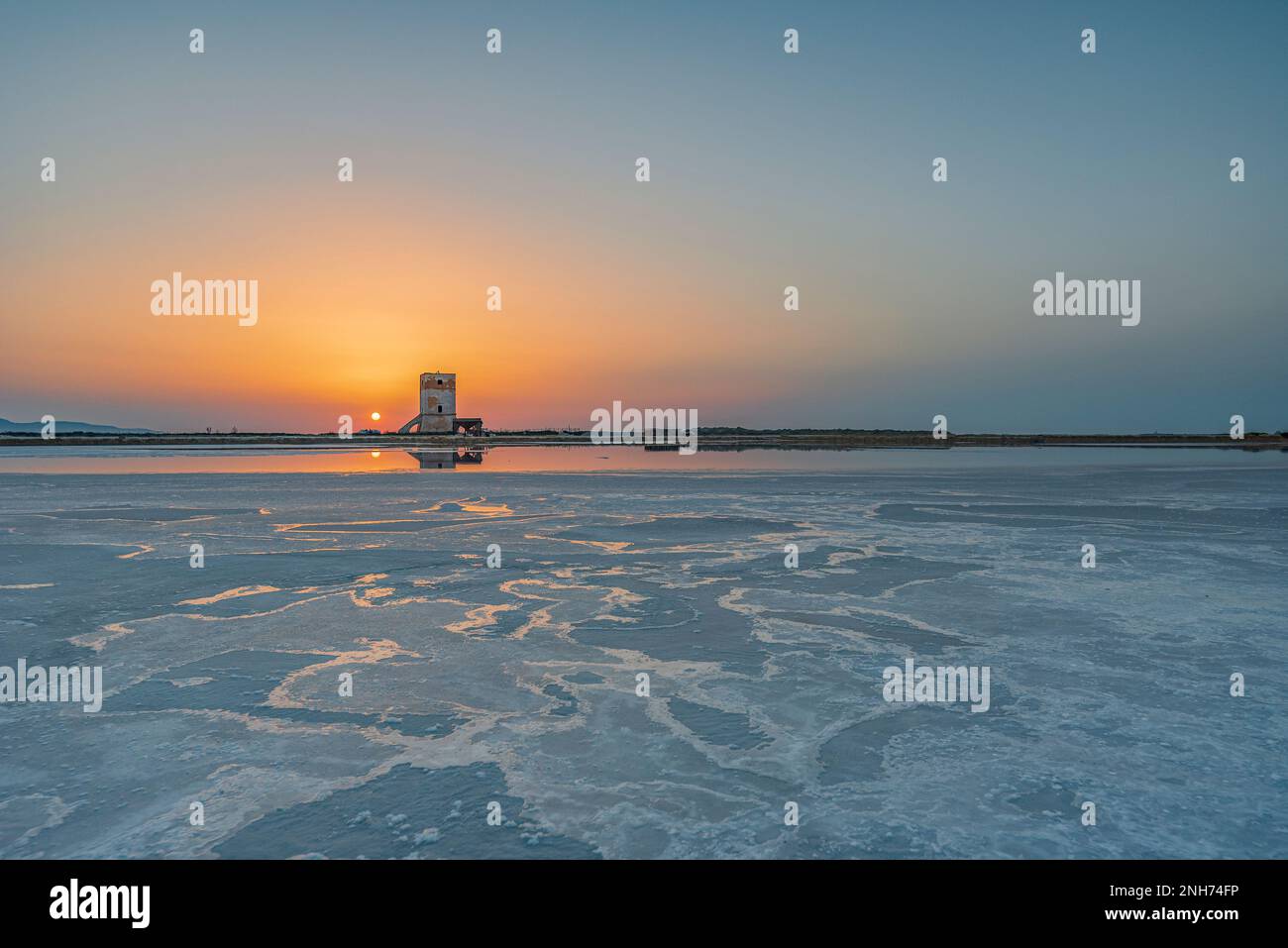 Sun setting behind the Nubia tower, salt pans of Trapani Stock Photo