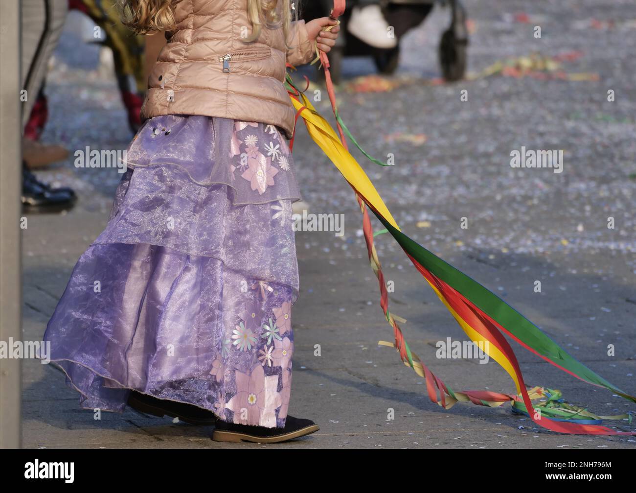 Child in carnival outifts play with confetti and streamers in the street Stock Photo