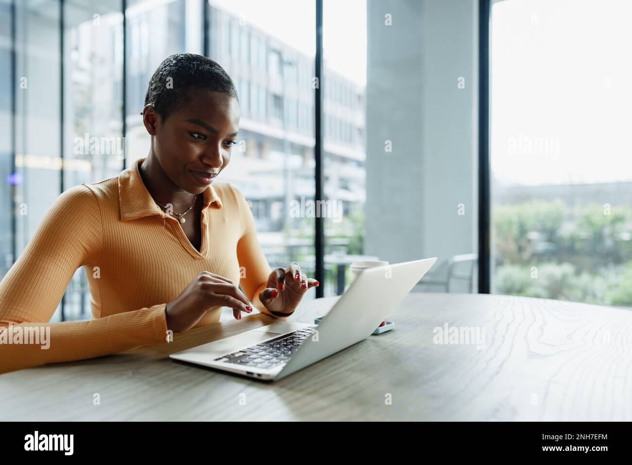 Young african woman freelancer working on laptop while sitting in ...