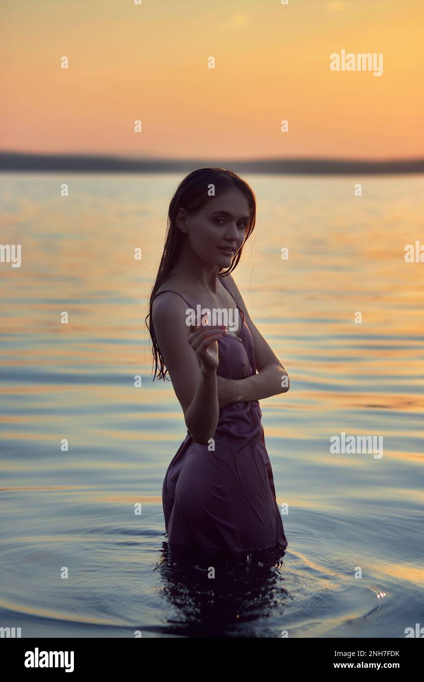 Beautiful young woman in the water at sunset. Natural beauty, long hair, woman in the lake Stock Photo