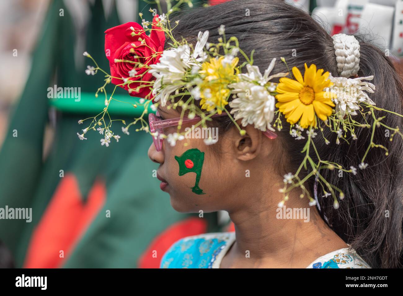 A kid seen with paint on her face and flowers on the head at the Martyr's Monument, or Shaheed Minar during the International Mother Language Day in Dhaka. Bangladeshis pay tribute at the Martyr's Monument, or Shaheed Minar, on International Mother Language Day in Dhaka, International Mother Language Day is observed in commemoration of the movement where a number of students died in 1952, defending the recognition of Bangla as a state language of the former East Pakistan, now Bangladesh. (Photo by Sazzad Hossain/SOPA Images/Sipa USA) Stock Photo