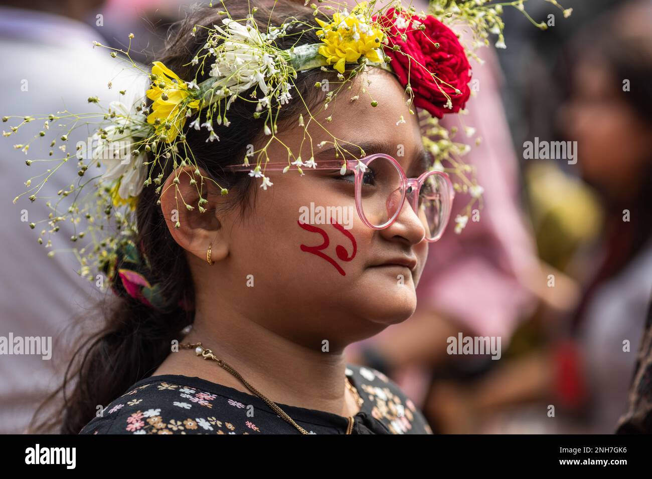 A kid seen with paint on her face and flowers on the head at the Martyr's Monument, or Shaheed Minar during the International Mother Language Day in Dhaka. Bangladeshis pay tribute at the Martyr's Monument, or Shaheed Minar, on International Mother Language Day in Dhaka, International Mother Language Day is observed in commemoration of the movement where a number of students died in 1952, defending the recognition of Bangla as a state language of the former East Pakistan, now Bangladesh. (Photo by Sazzad Hossain/SOPA Images/Sipa USA) Stock Photo