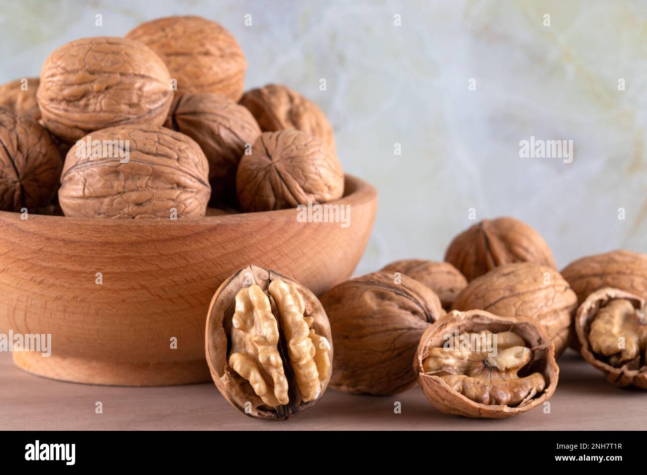 Walnut kernels and cracked walnuts on wooden background, front view Stock Photo
