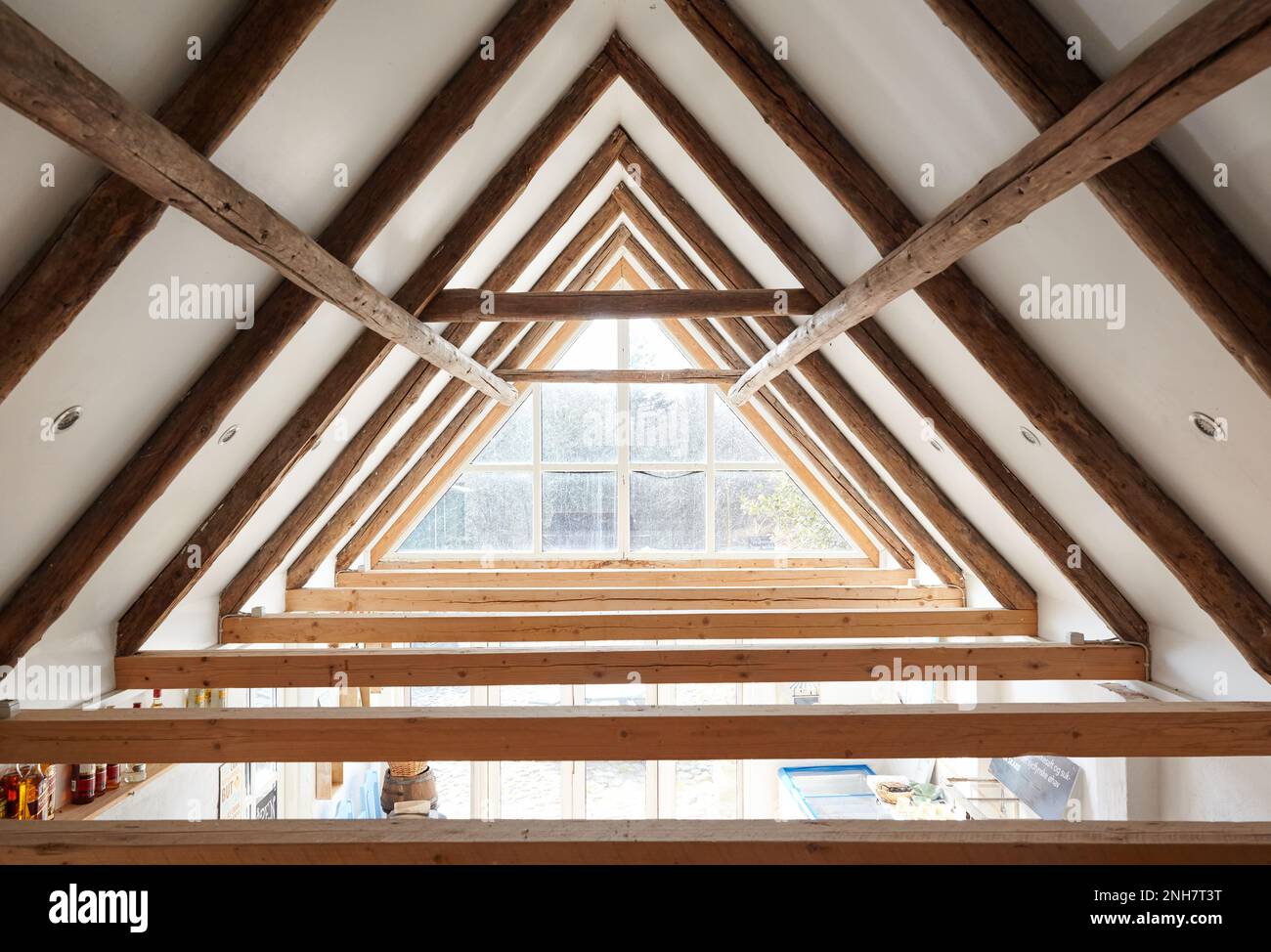 Very authentic architecture of a ceiling/attic, with visible brown frameworks, a big window makes it very bright and luminous. Huge ceiling high. Stock Photo