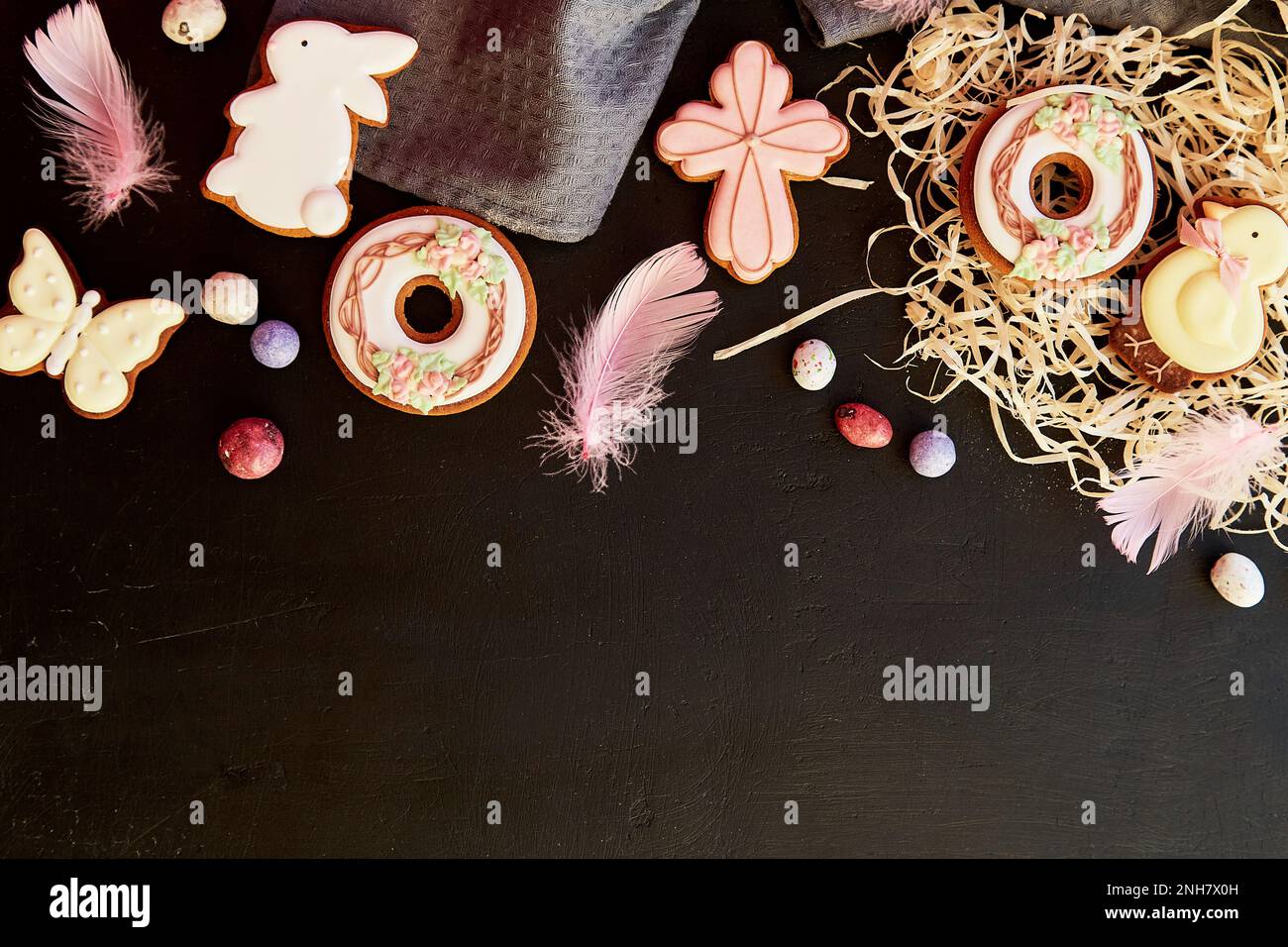 Happy Easter festive cookies decorated with feathers on black background flat lay, copy space. Easter banner. Stock Photo