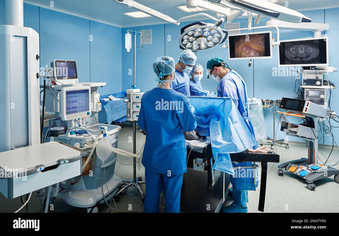 Group of concentrated surgeons while surgical operation in operating theater with nurses and assistants Stock Photo