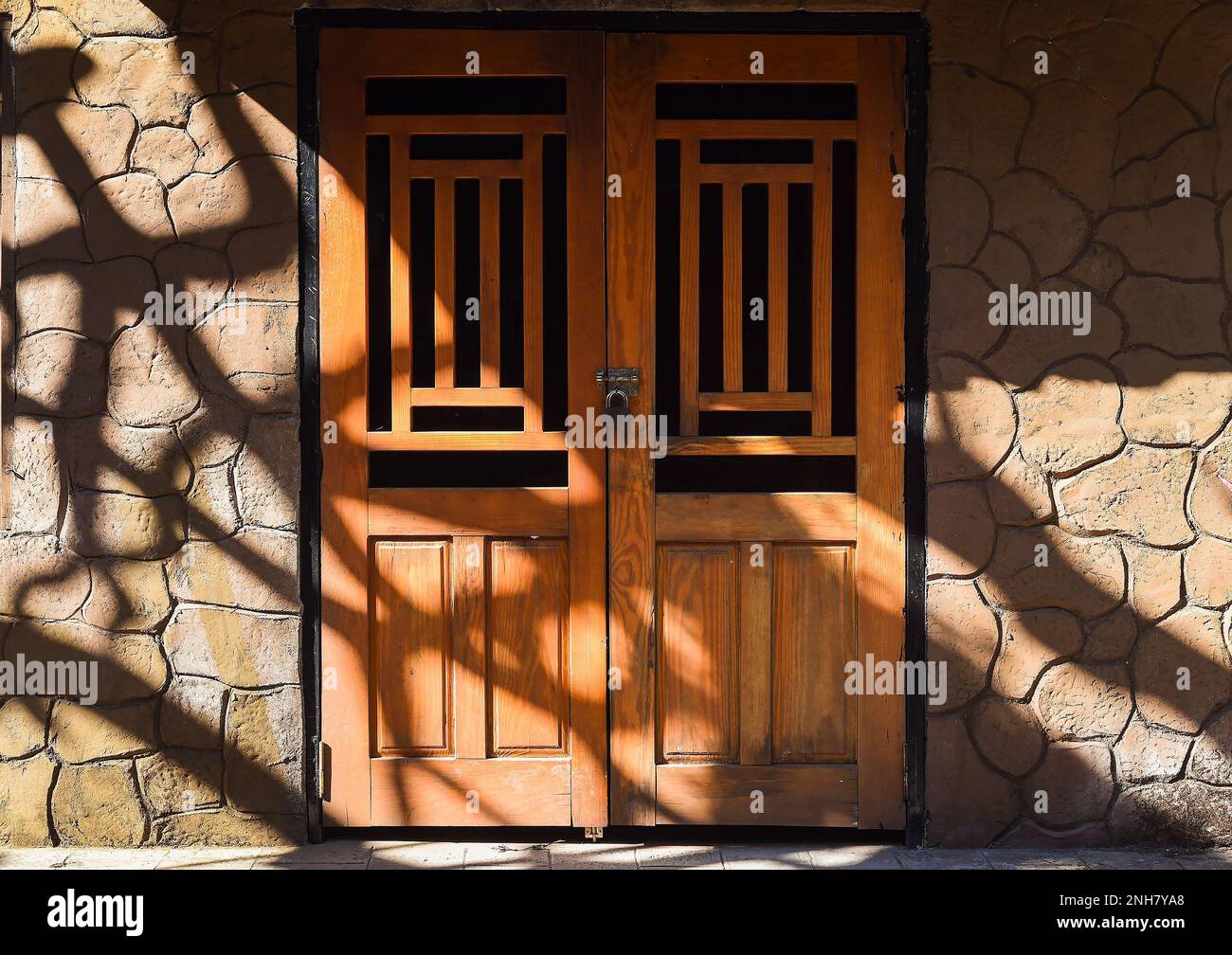 Closed wooden door with hanging door lock under sun rays Stock Photo