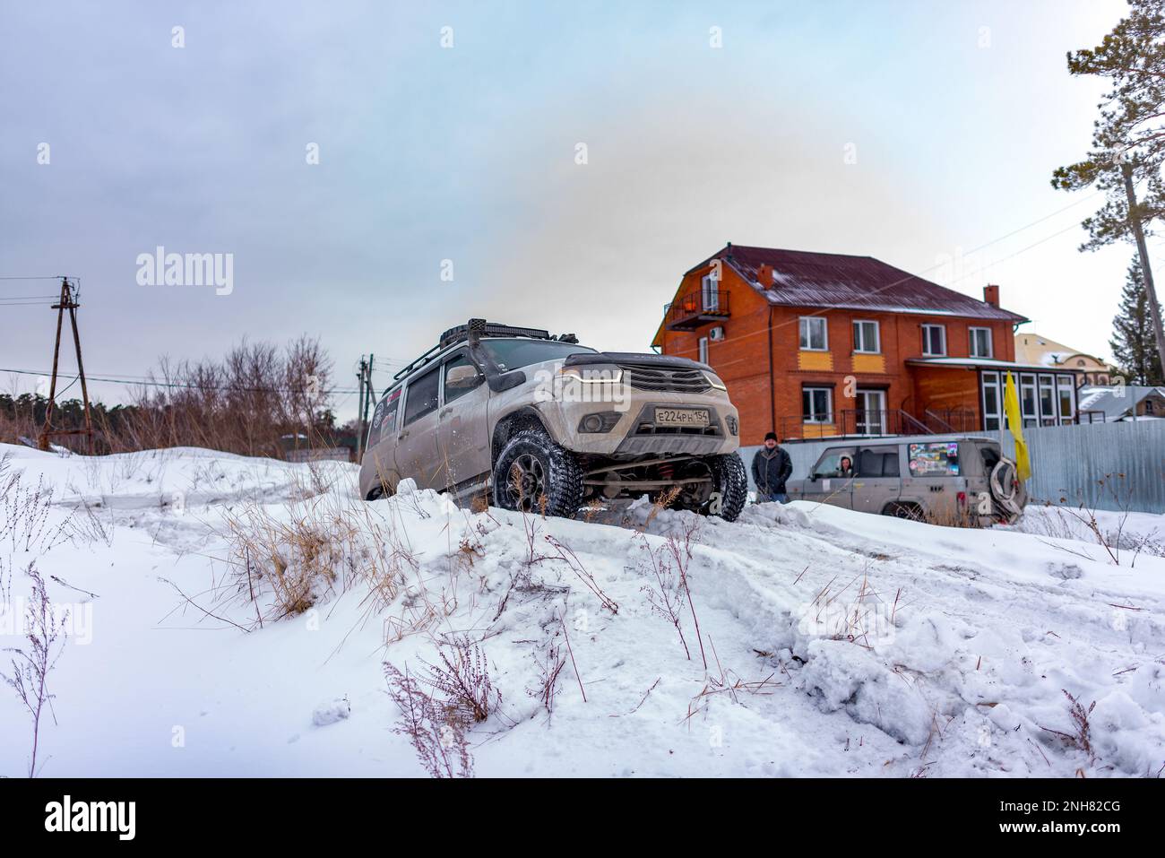 Russian white SUV 'UAZ Patriot' drives on a snow hill in winter. Stock Photo