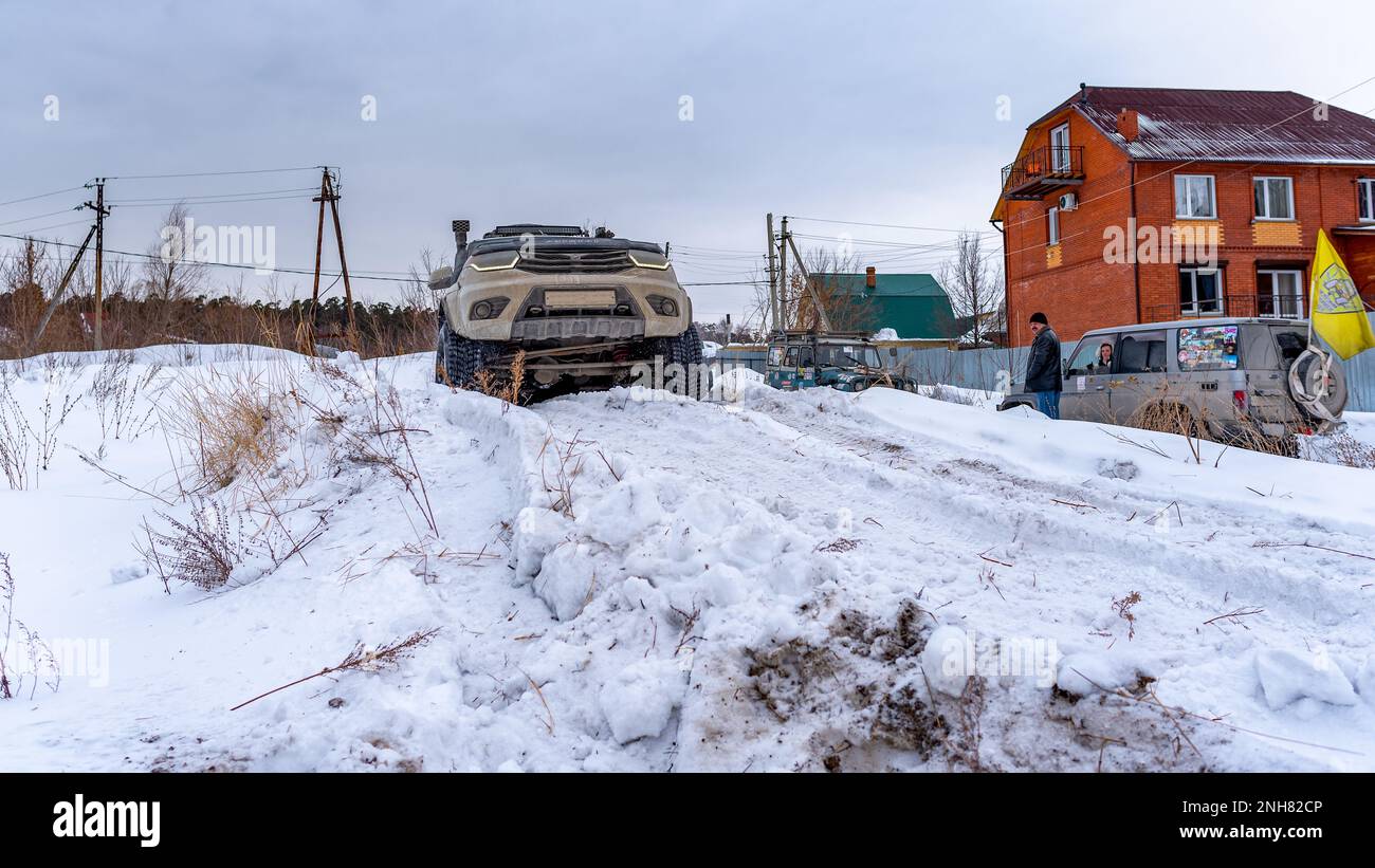 Russian white SUV 'UAZ Patriot' drives on a snow hill in winter. Stock Photo