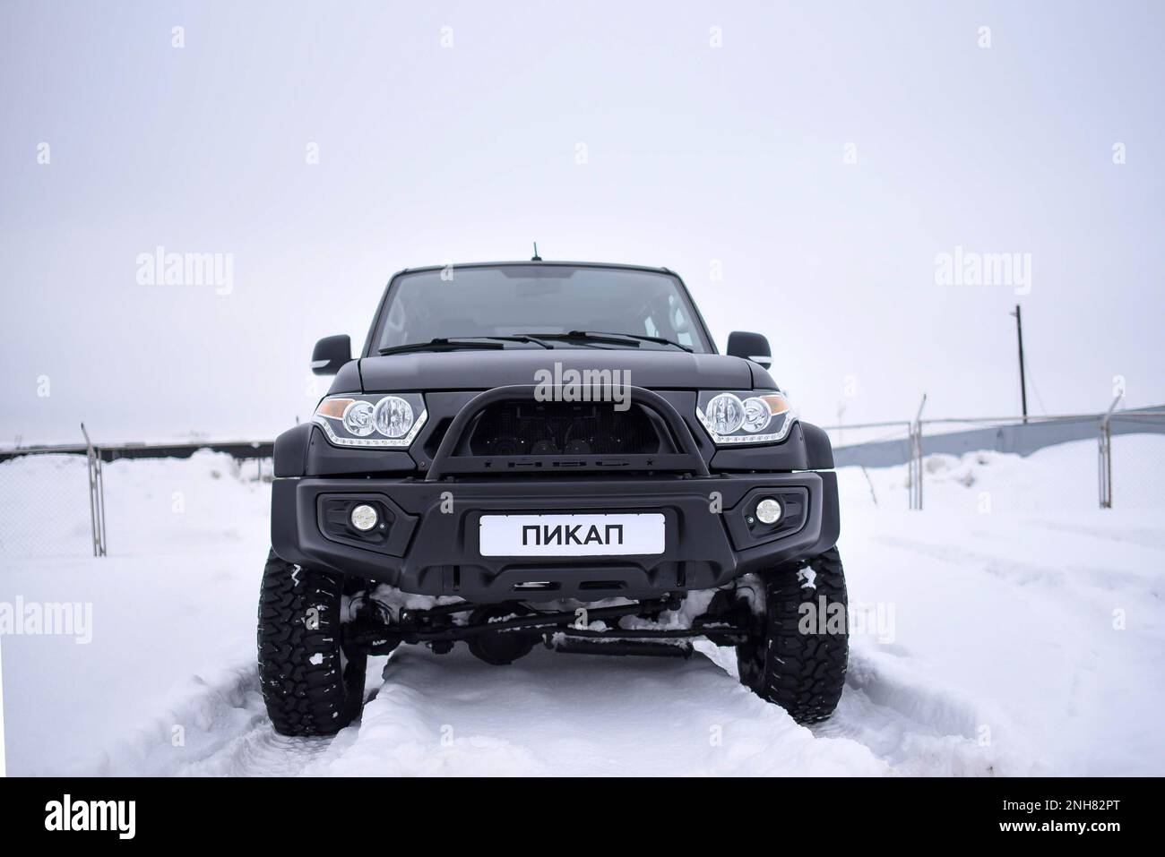 Russian black 4x4 SUV 'UAZ Patriot' with the inscription 'pickup' on the number is standing in the snow. Stock Photo