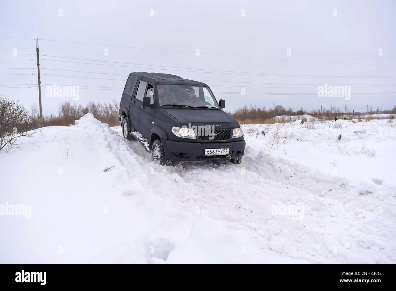Russian black 4x4 SUV in protective paint Raptor 'UAZ Patriot Pickup' quickly moves off a snow Bank in the winter. Stock Photo