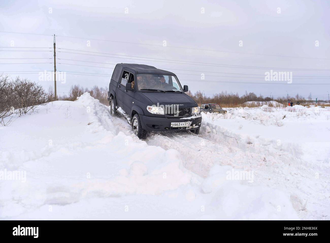 Russian black 4x4 SUV in protective paint 'UAZ Patriot Pickup' is driving fast on the road in the snow in winter. Stock Photo