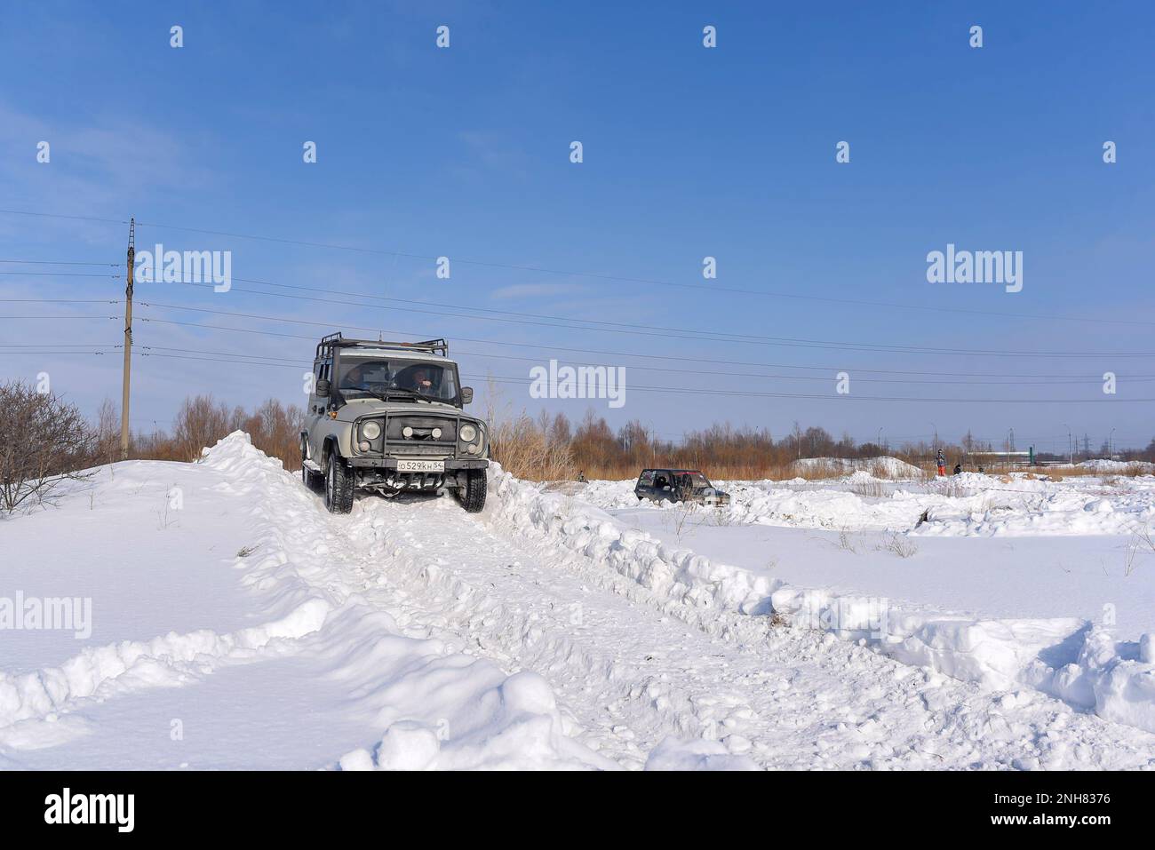 Russian offroad SUV 'UAZ hunter 469' 4x4 rides on a snowy mountain in winter in a field on a bad road. Stock Photo
