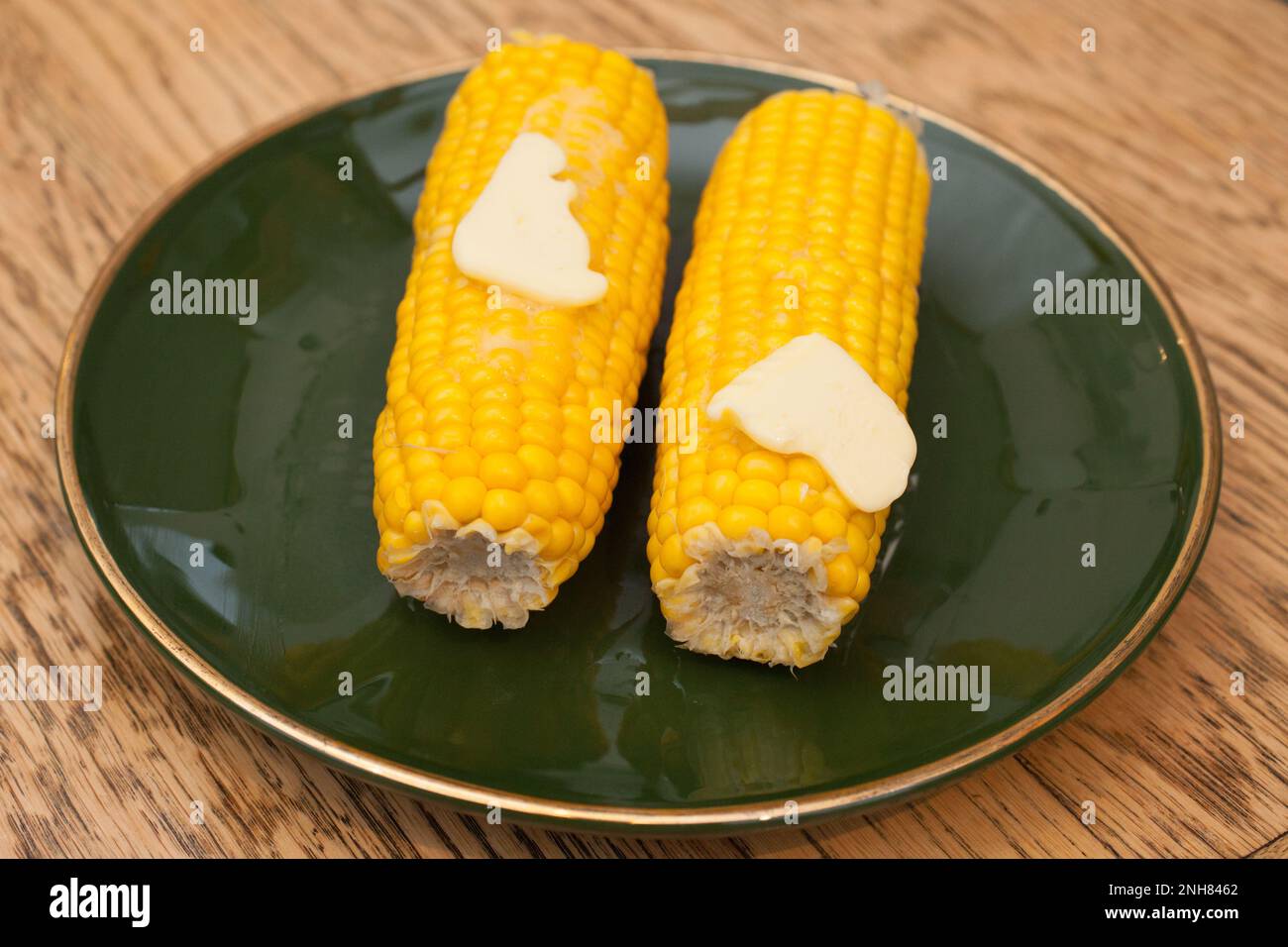 Two corn on the cobs with melted butter Stock Photo