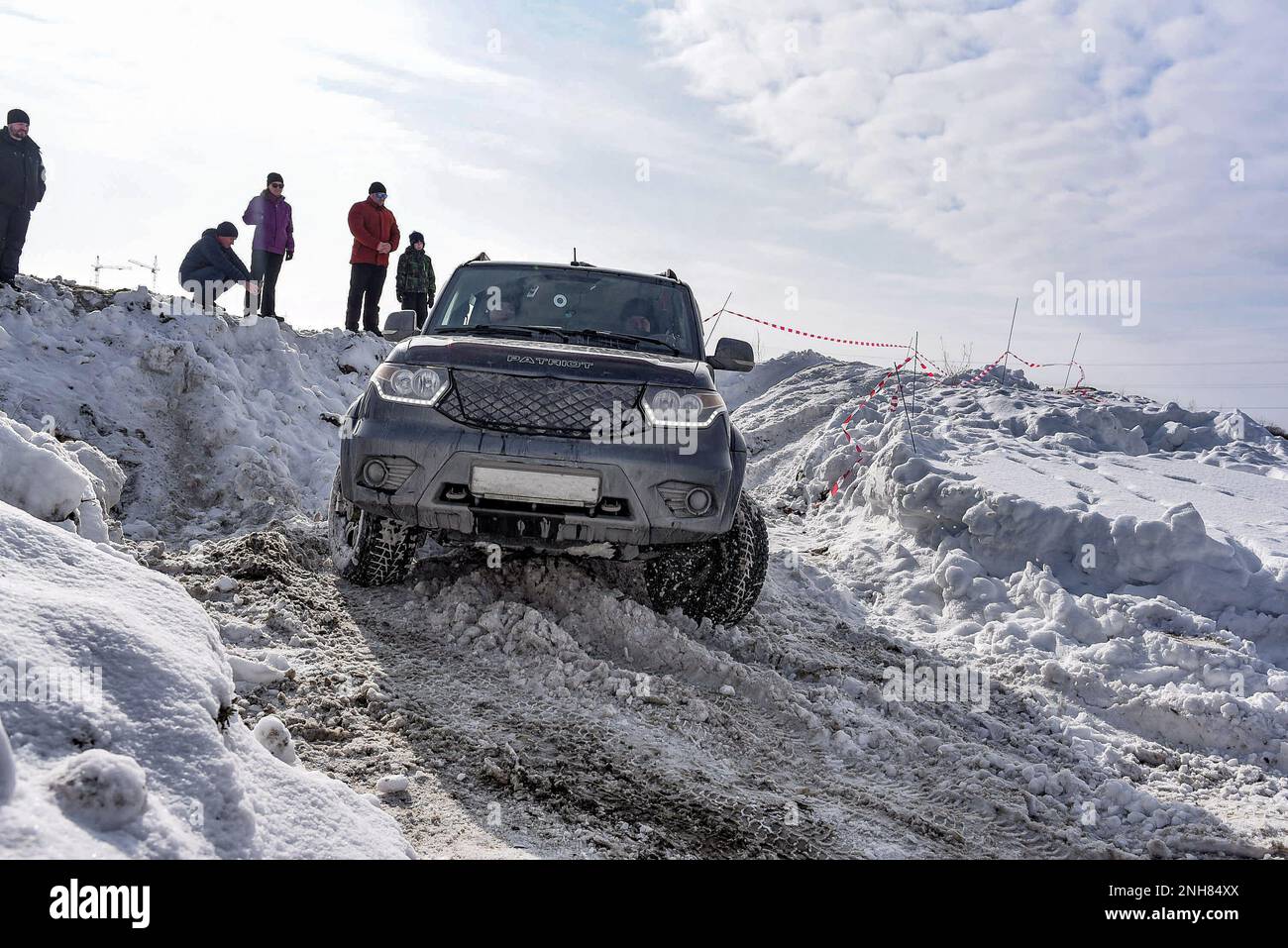 Russian SUV 'UAZ Patriot' quickly goes on a snowy road in the field in winter, clinging to the bumper snowstorm wheel. Stock Photo