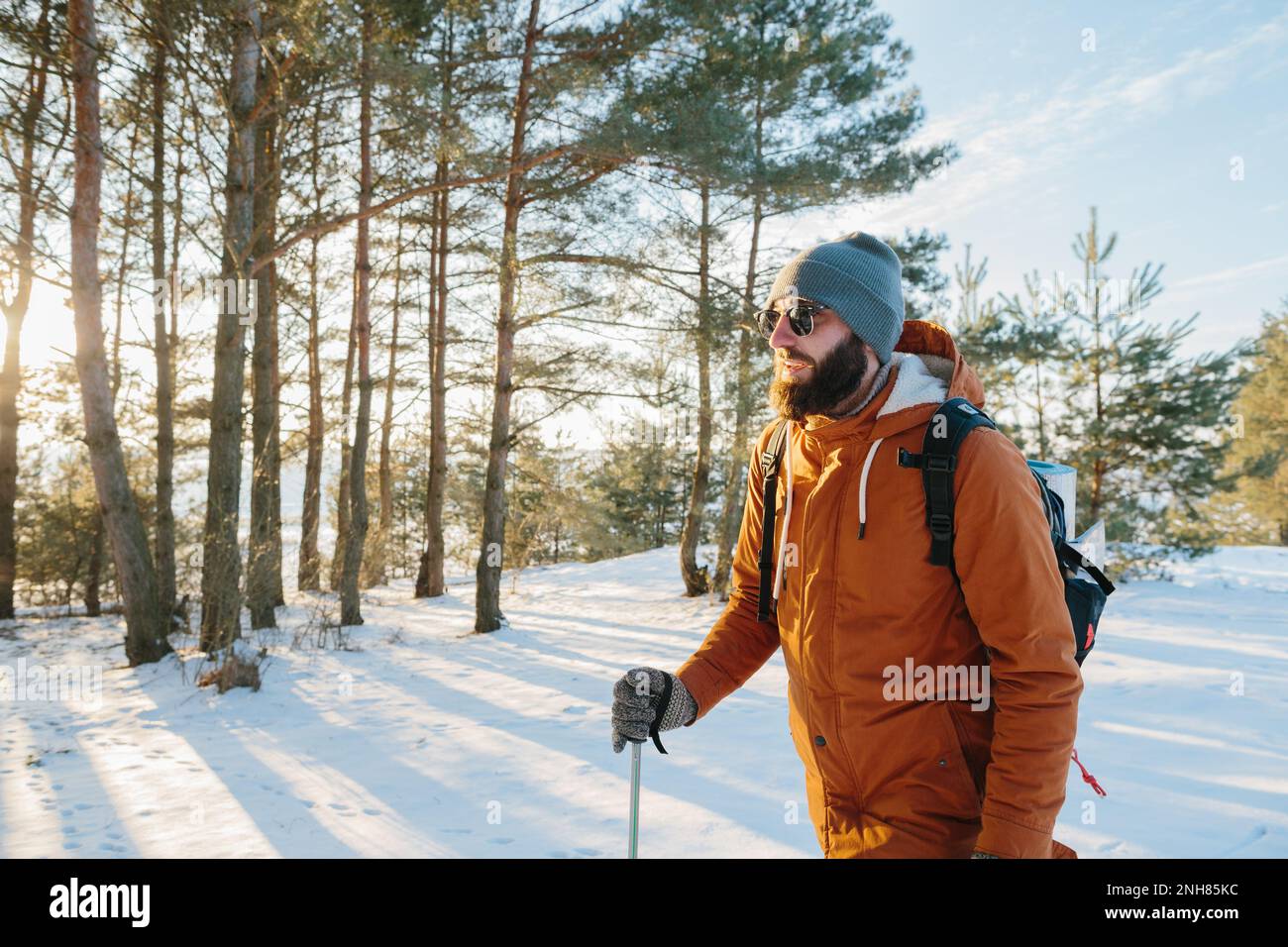 Winter landscape, a man with a backpack and warm winter clothes in the forest, traveling in the