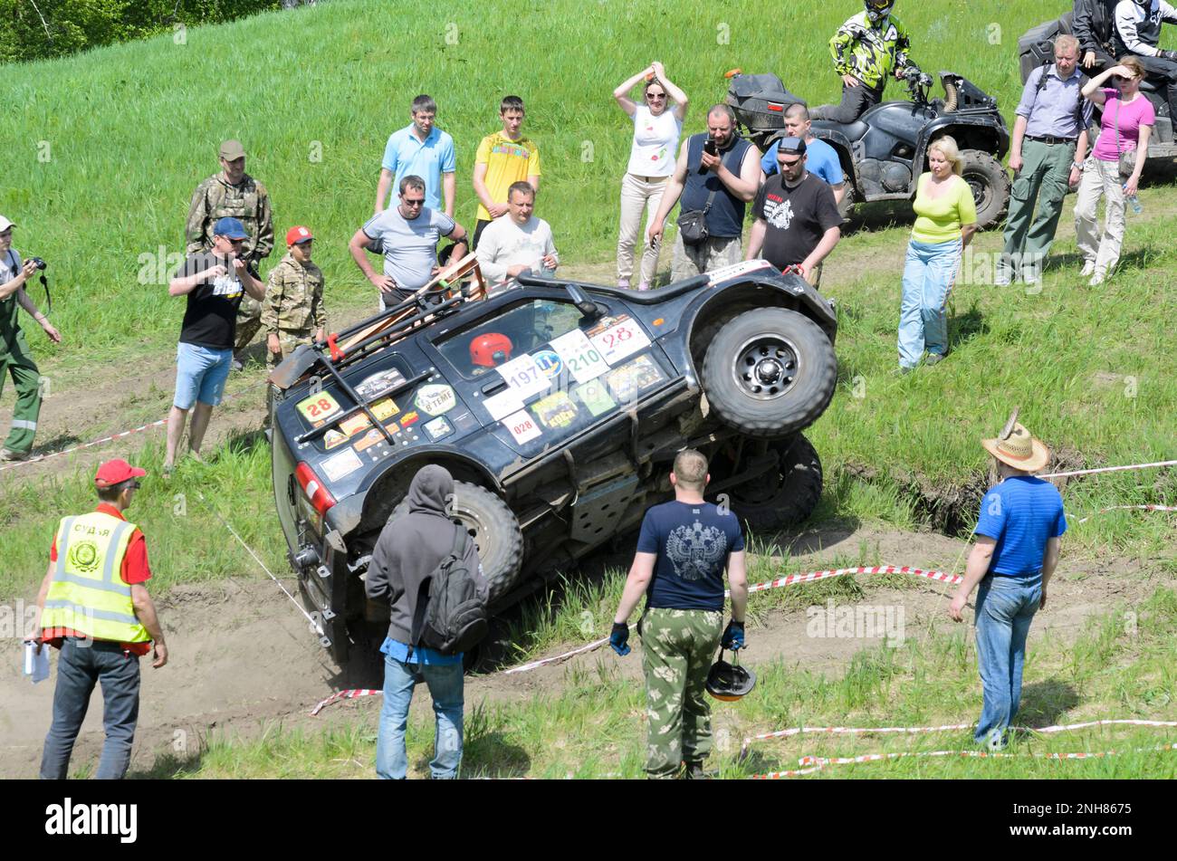Crowd of spectators looking at the car 'Suzuki Jimny' which is highly raised rims at the entrance to the mountain on the competition in Novosibirsk Stock Photo
