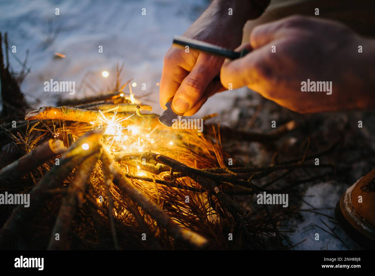 Male hand starts fire with magnesium fire steel, fire striker Stock Photo