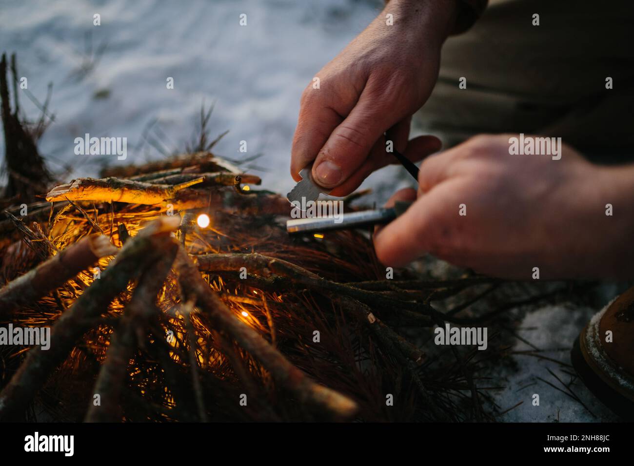 Male hand starts fire with magnesium fire steel, fire striker Stock