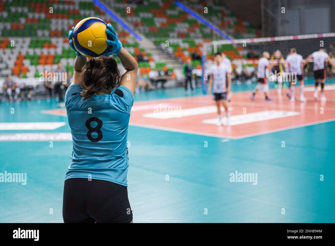 Girl with disposable gloves passing ball during volleyball match Stock