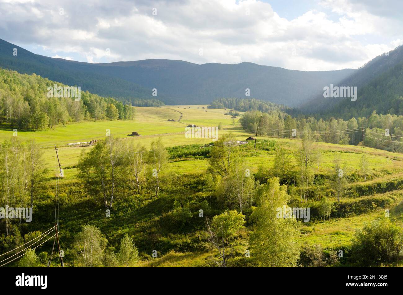 Sloping field under the hill, under a cloudy sky. Stock Photo