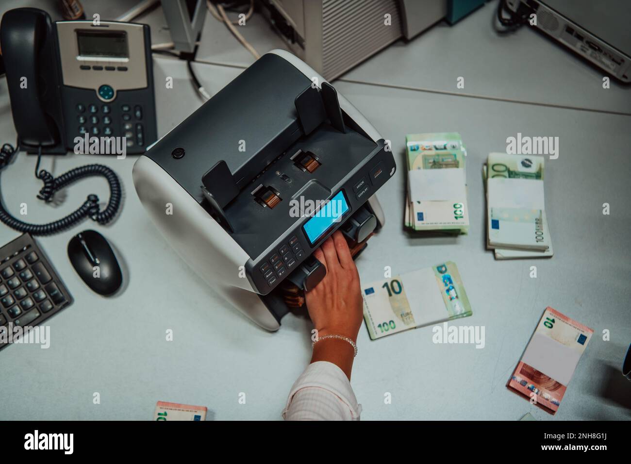 Bank employees using money counting machine while sorting and counting ...