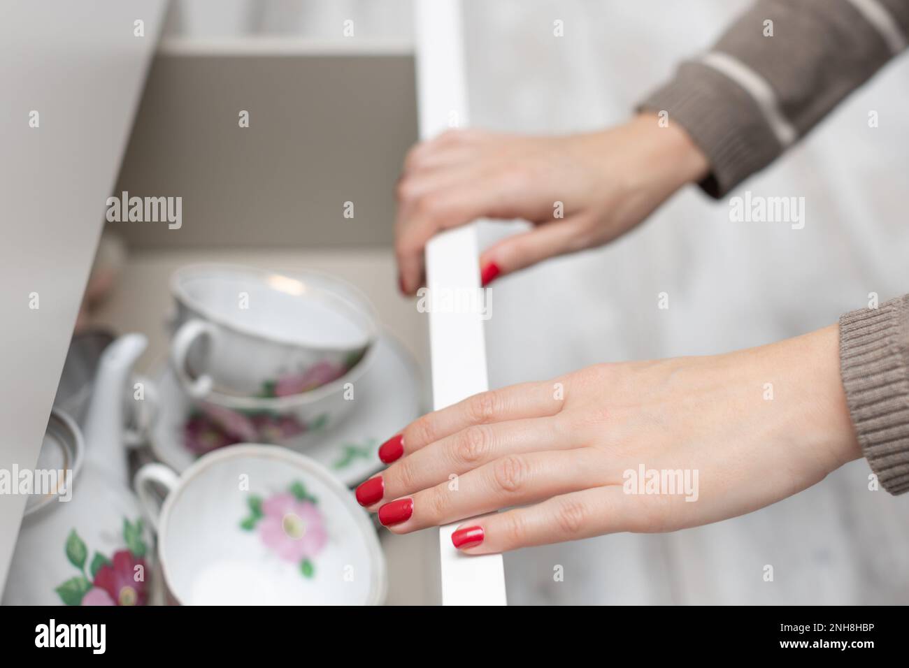 woman opens a drawer with dishes in the kitchen. man opens cupboard