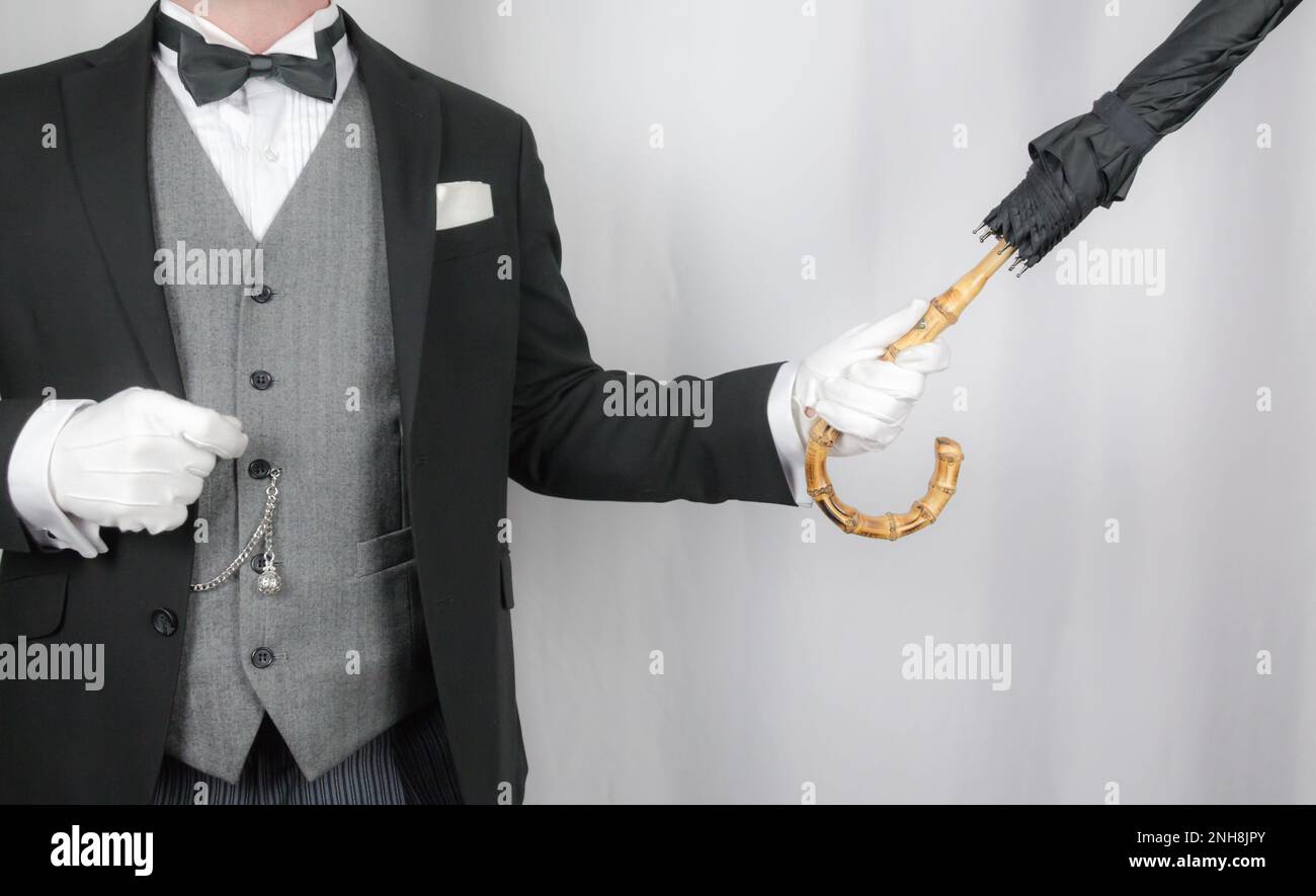 Portrait of Butler or Concierge in Dark Suit and White Gloves Holding Umbrella. Service Industry and Professional Hospitality. Stock Photo