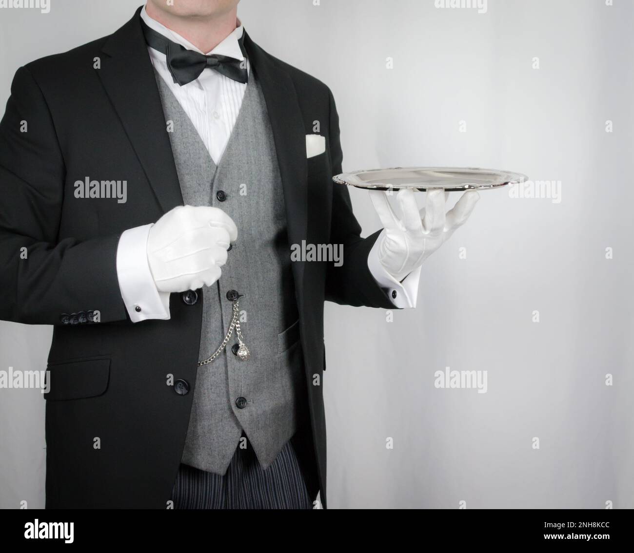 Portrait of Butler or Waiter in Dark Formal Suit Holding Silver Tray. Concept of Service Industry and Professional Hospitality. Stock Photo