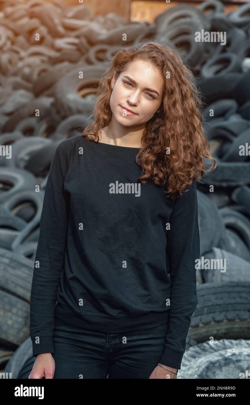 Dramatic photo of a sad girl at tire repair dump. Waste disposal Stock