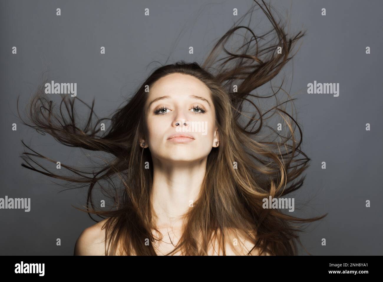 girl with flowing hair in the air studio portrait against gray