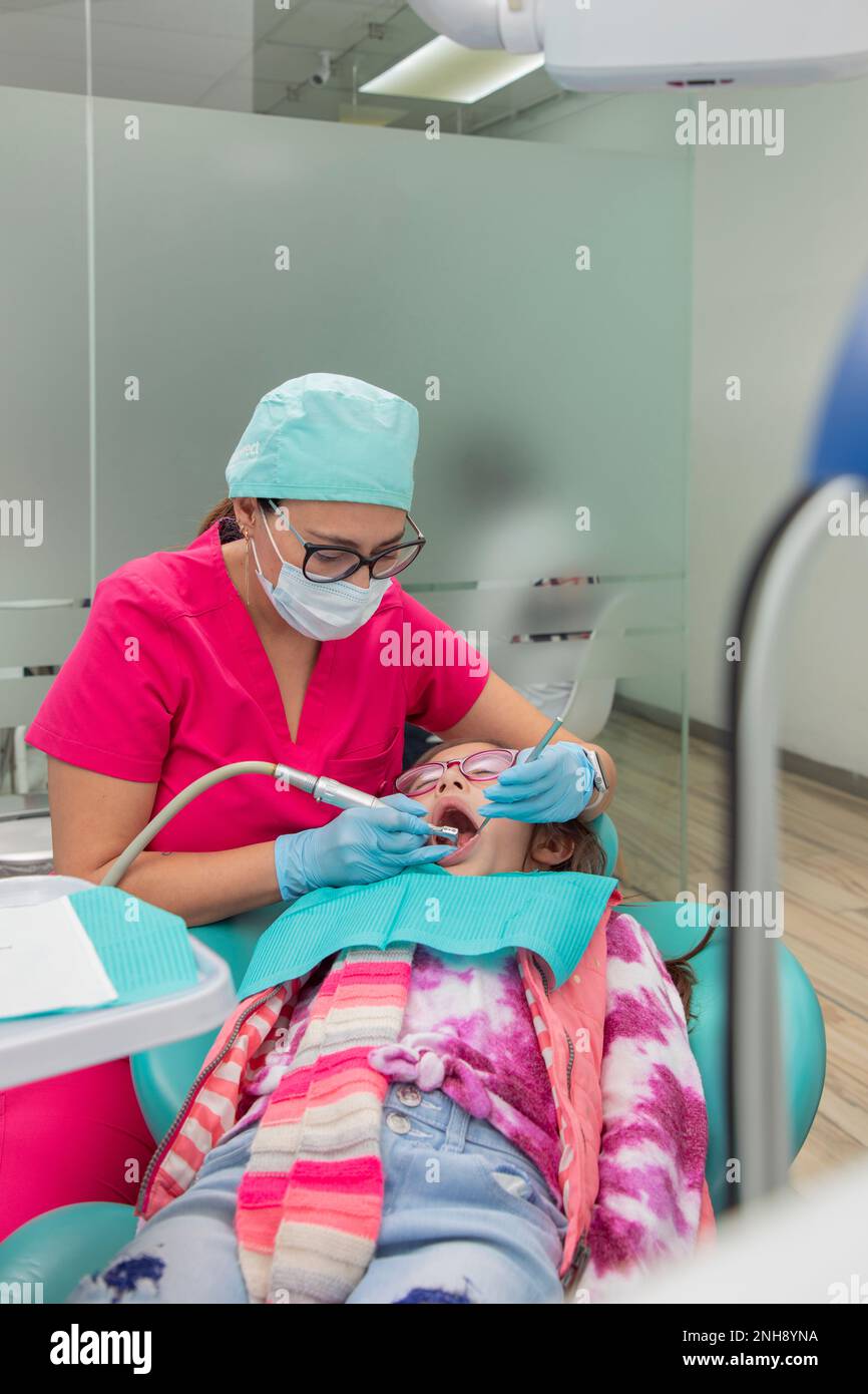 Dentist cleaning the teeth of a girl lying on the chair in the dental
