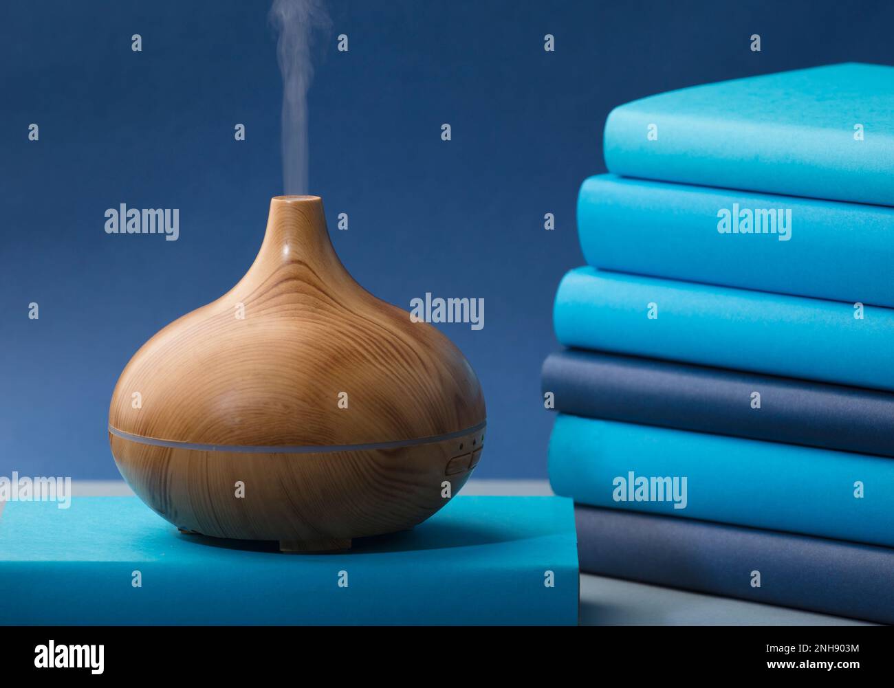 wood fragrance on the desk table with natural oils essence vapor, with blue and teal colored books Stock Photo