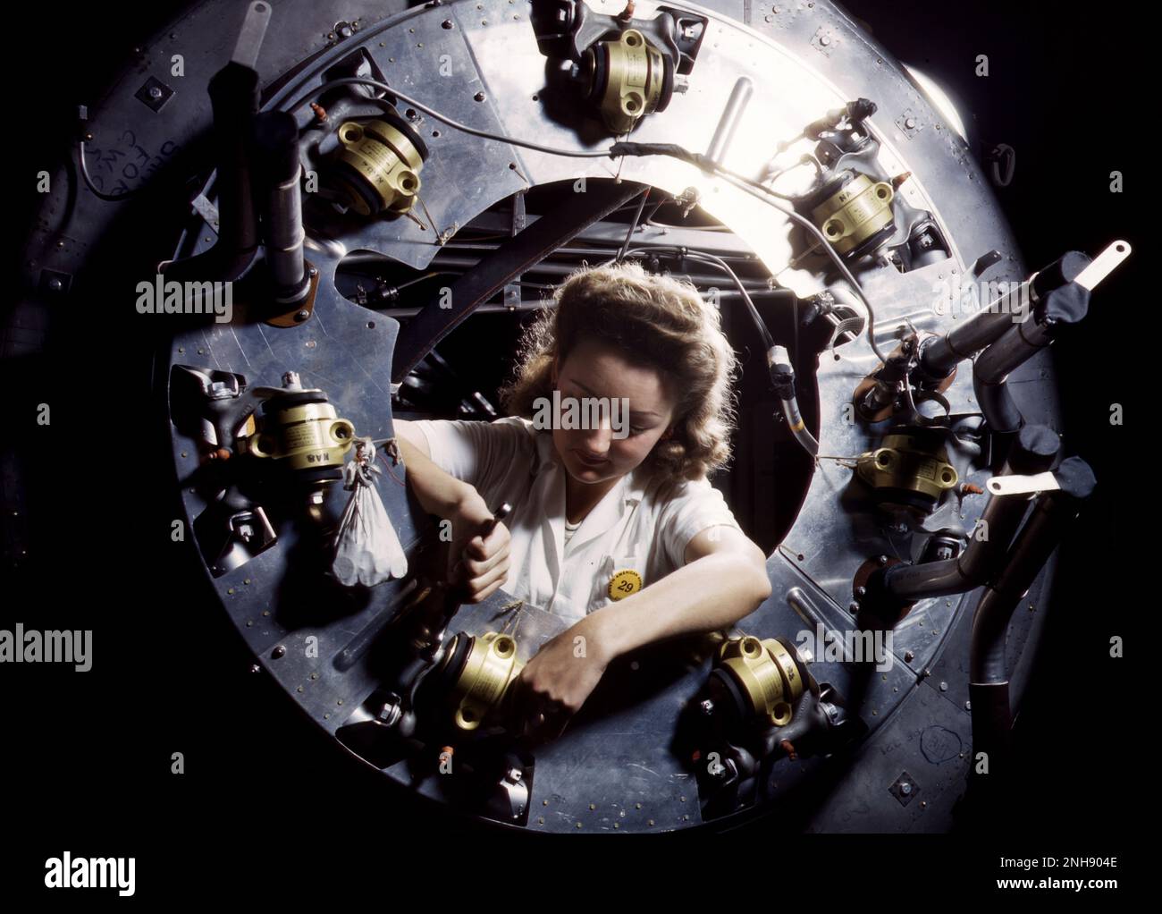 Female worker assembling the cowling for one of the motors for a B-25 bomber in the engine department of North American [Aviation, Inc.]'s Inglewood, California, plant during World War II. Photographed by Alfred T. Palmer, October, 1942. Stock Photo