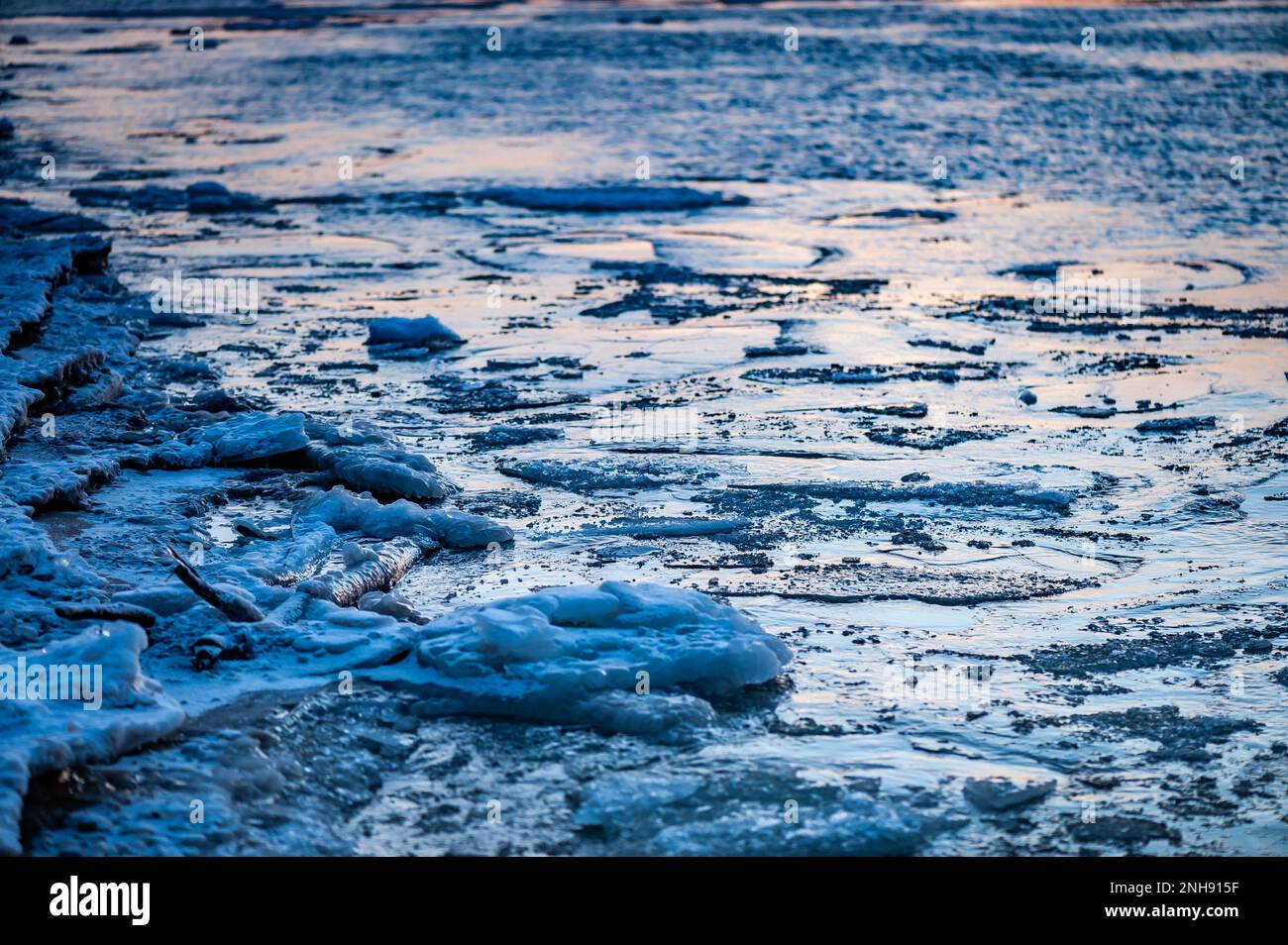 Ice fragments covered with snow on frozen river water. Dark blue ...